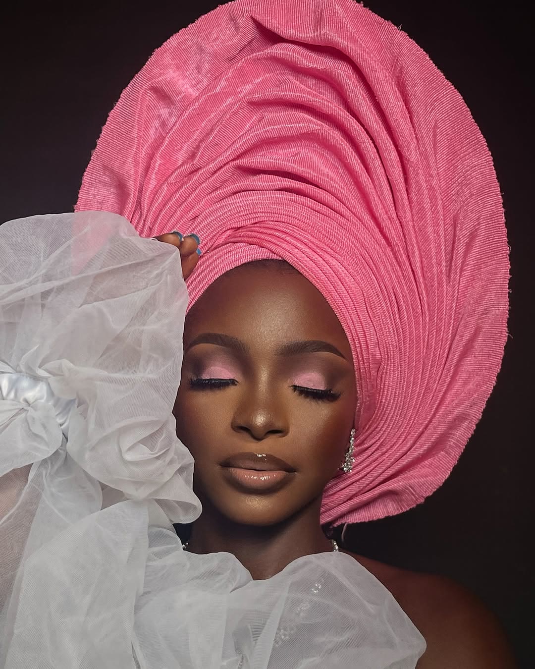 Client in a pink gele with eyes closed showing pink eyeshadow