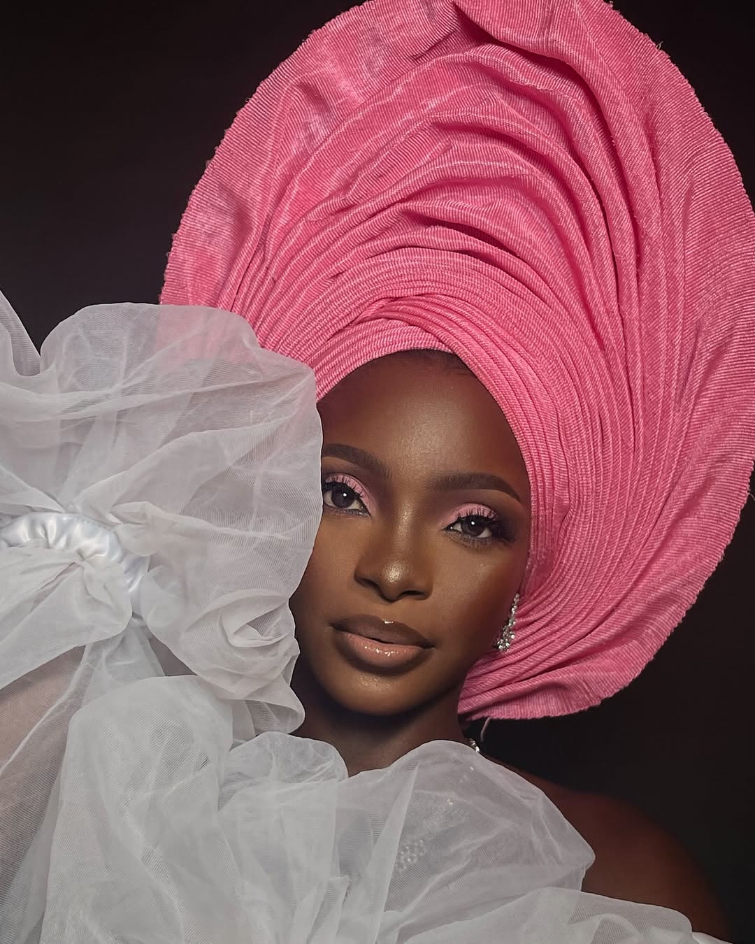Client in a pink gele with soft pink eye makeup and a glossy nude lip